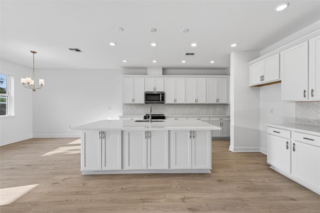 983 Fiesta Key Circle Lady Lake, FL 32159 - Photo 6 of 39 a kitchen with stainless steel appliances granite countertop a stove a sink a refrigerator and white cabinets