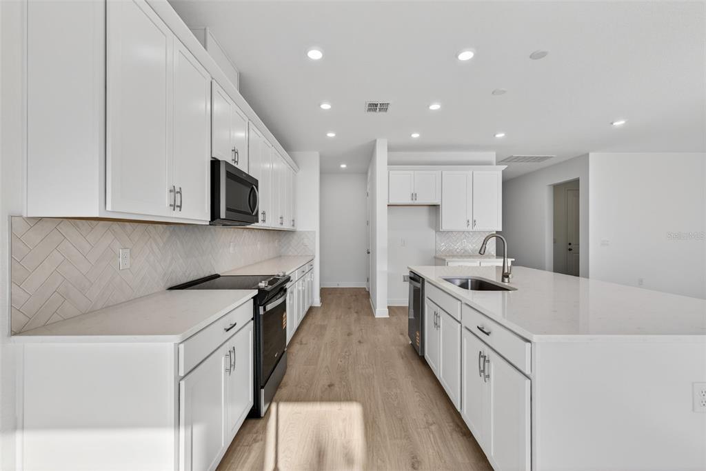 983 Fiesta Key Circle Lady Lake, FL 32159 - Photo 8 of 39 a kitchen with stainless steel appliances granite countertop a sink stove and microwave