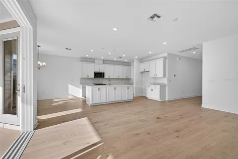 a view of a kitchen with white cabinets and wooden floor