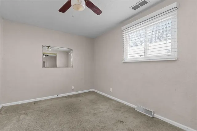 an empty room with ceiling fan and window