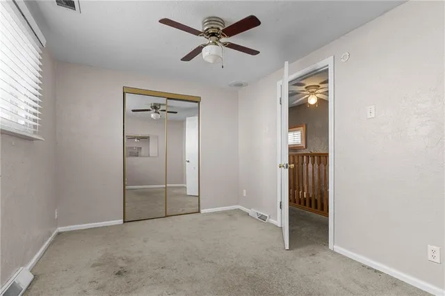 an empty room with closet and a ceiling fan