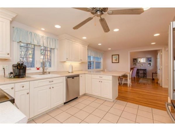 3 McLain Drive Pelham, NH 03076 - Photo 6 of 34 a open kitchen with white cabinets a sink dishwasher a dining table and chairs with wooden floor