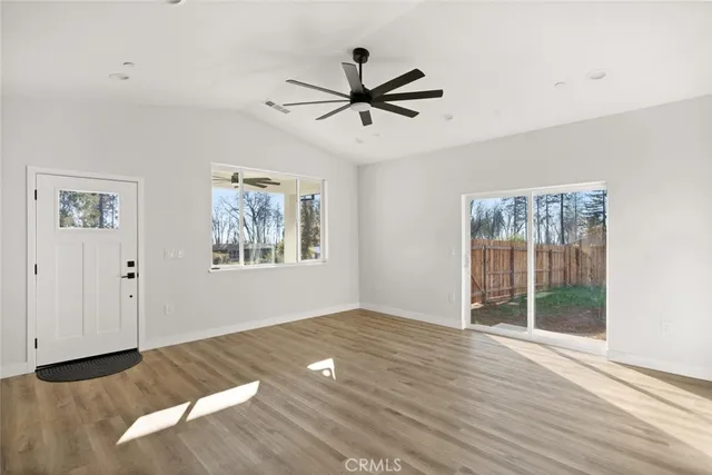 a view of empty room with wooden floor and fan