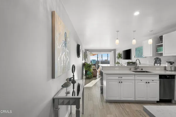 a large white kitchen with a sink and dishwasher a stove with wooden floor