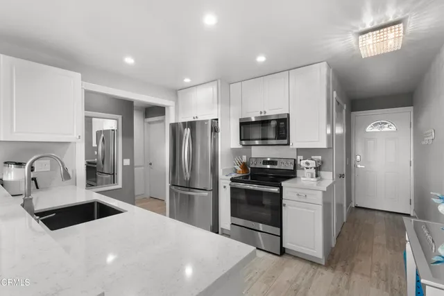 a kitchen with granite countertop a refrigerator stove and sink