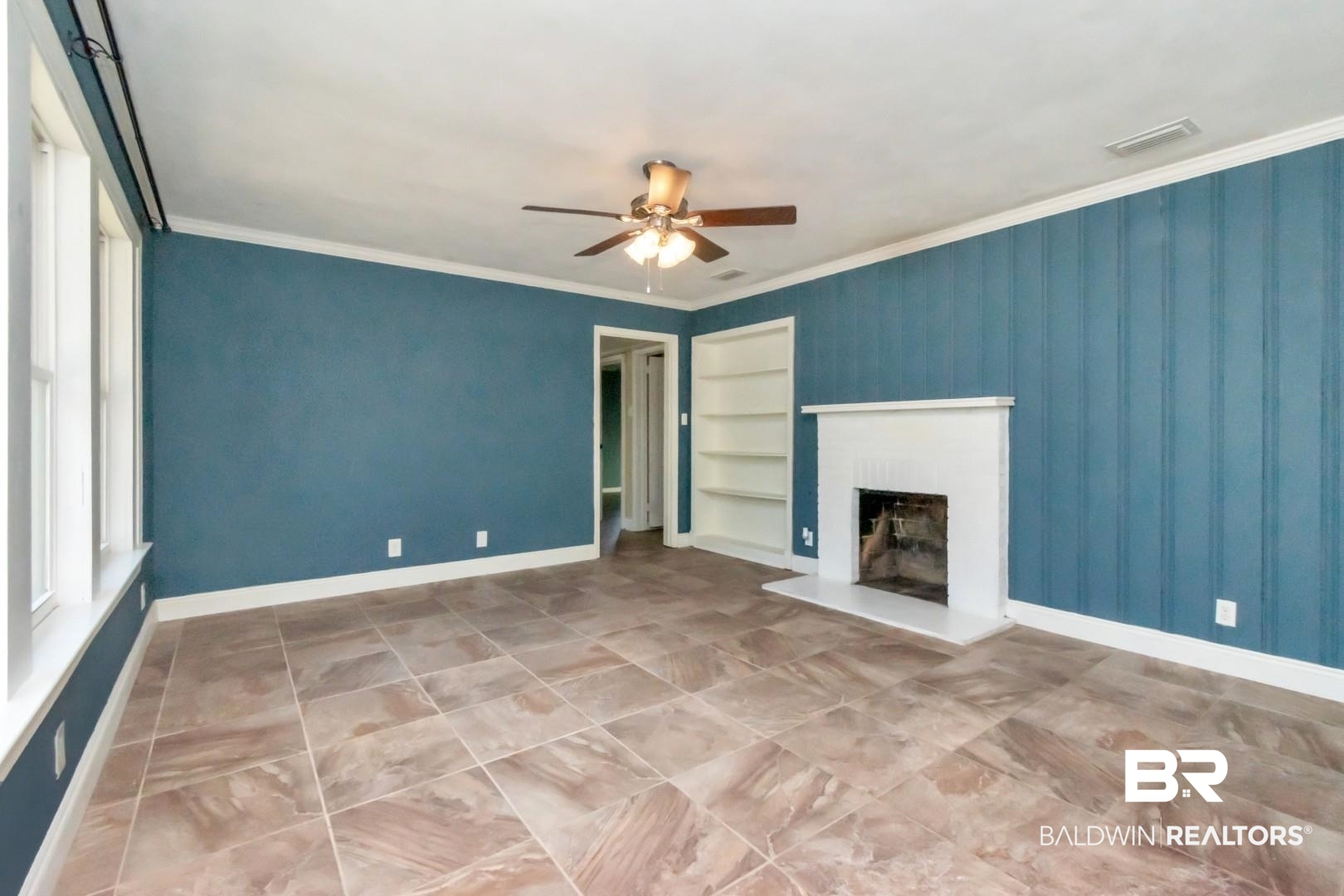 410 St John Place Mobile, AL 36609 - Photo 2 of 32 Unfurnished living room featuring built in features, a ceiling fan, a fireplace with raised hearth, and crown molding