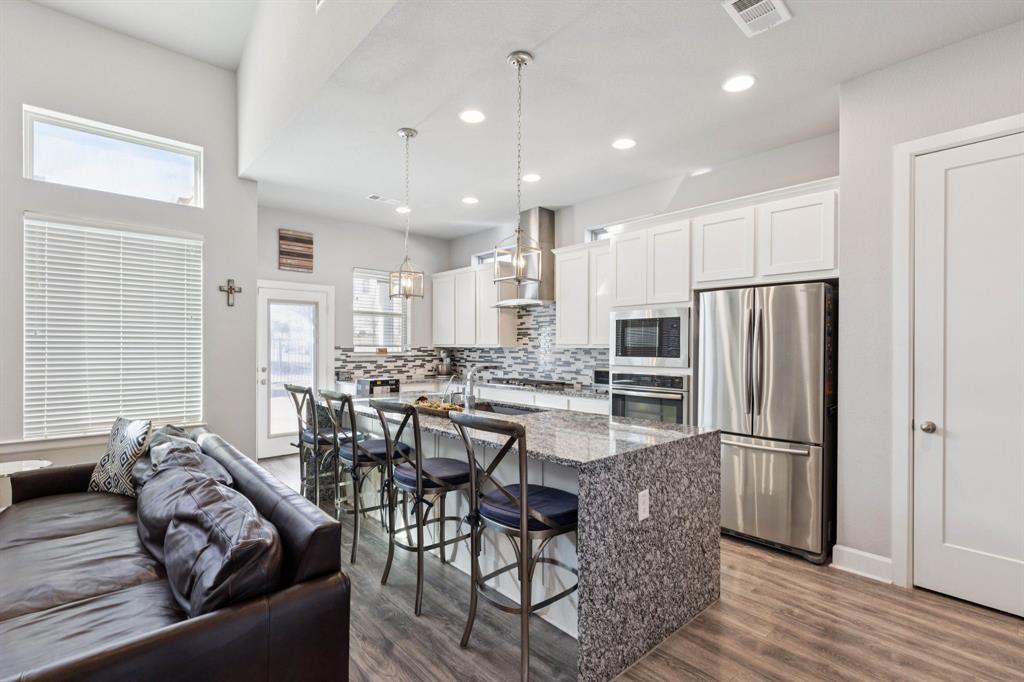 2000 Crescent Street Fort Worth, TX 76008 - Photo 9 of 40 a kitchen with stainless steel appliances granite countertop a refrigerator a stove a sink a dining table and chairs with wooden floor