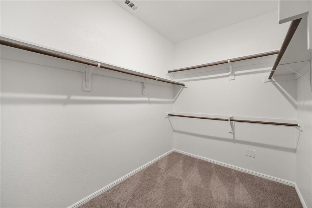 6910 Prairieside Trail Venus, TX 76084 - Photo 23 of 40 Spacious closet featuring white walls, ample shelving, and carpeted flooring in the primary suite.