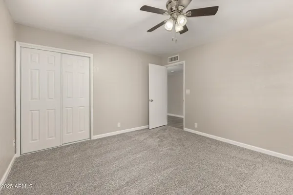 an empty room with windows and fan