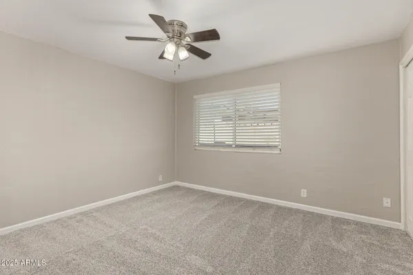 an empty room with a chandelier fan and windows