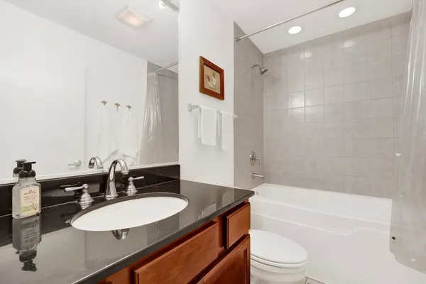 a bathroom with a bathtub shower sink vanity mirror and toilet