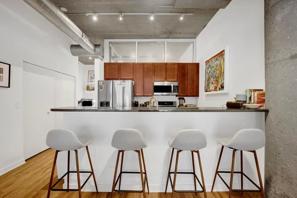 a kitchen with stainless steel appliances a white table chairs and a refrigerator