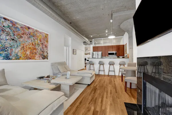a living room with stainless steel appliances furniture a rug and a kitchen view