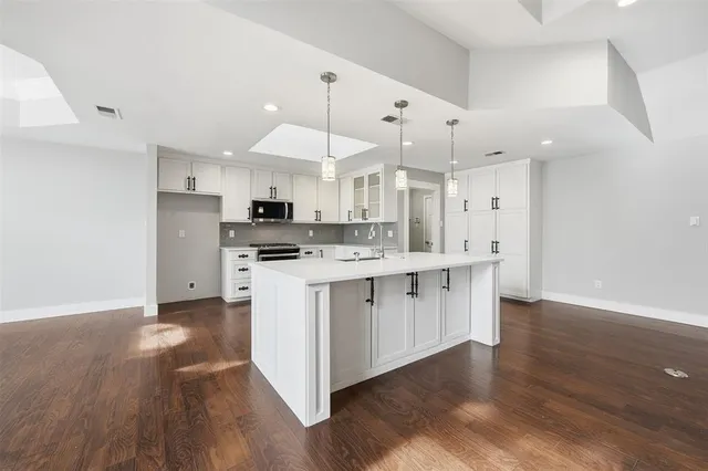 a kitchen with stainless steel appliances kitchen island a sink a stove a refrigerator and a window