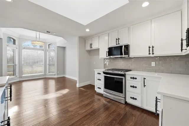 a kitchen with stainless steel appliances granite countertop a stove and a white cabinets