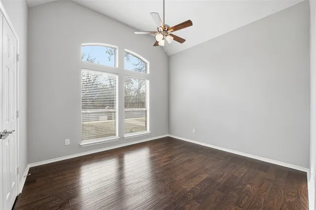 an empty room with wooden floor fan and windows