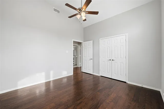 an empty room with wooden floor fan and windows