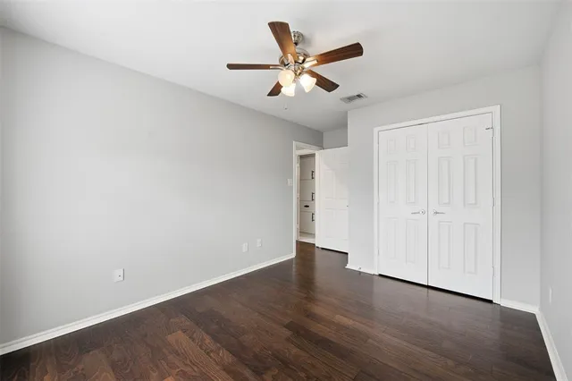 an empty room with wooden floor and ceiling fan