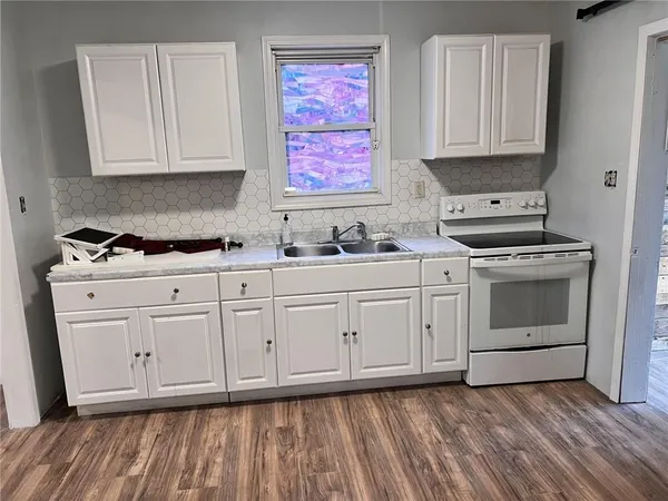 a kitchen with white cabinets stainless steel appliances and wooden floor