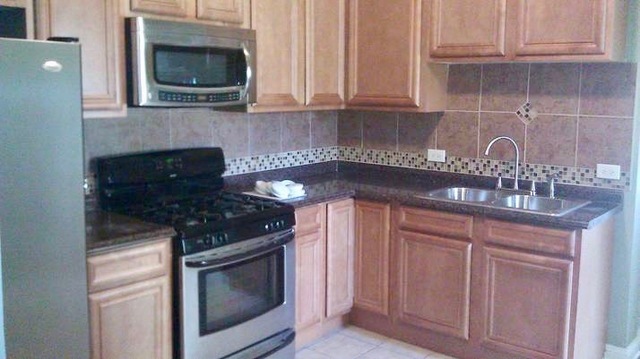 5708 South Aberdeen Street Chicago, IL 60621 - Photo 18 of 25 a kitchen with granite countertop white cabinets and stainless steel appliances
