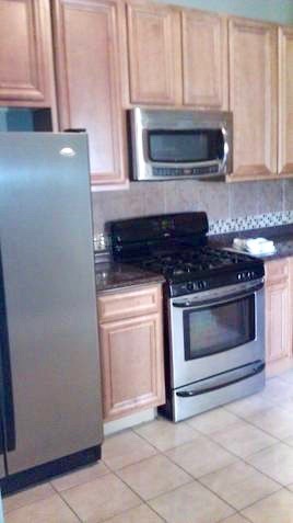 5708 South Aberdeen Street Chicago, IL 60621 - Photo 19 of 25 a kitchen with granite countertop white cabinets and stainless steel appliances