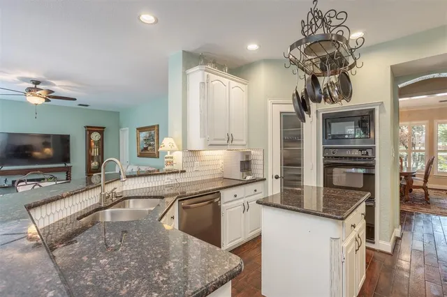 a kitchen with stainless steel appliances granite countertop a sink a stove and a wooden floors