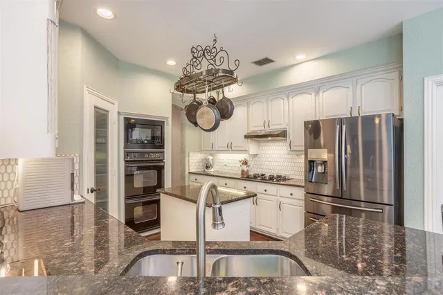 a kitchen with stainless steel appliances granite countertop a refrigerator a stove and a sink