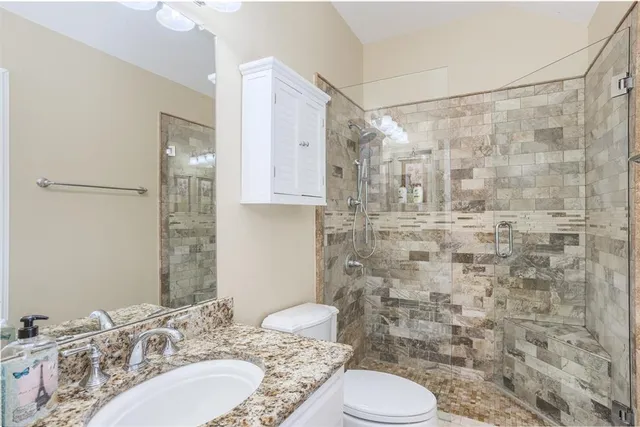 a bathroom with a granite countertop sink toilet and shower