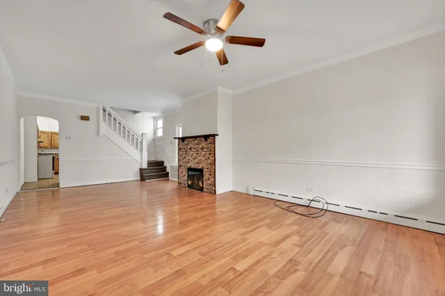 wooden floor in an empty room with a fireplace and a window