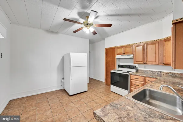 a kitchen with stainless steel appliances a sink a stove a refrigerator cabinets and a dining table