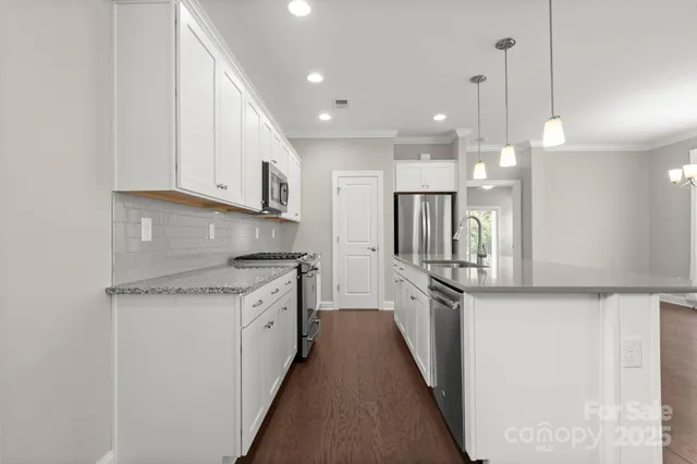a kitchen with stainless steel appliances granite countertop a sink a stove and a refrigerator