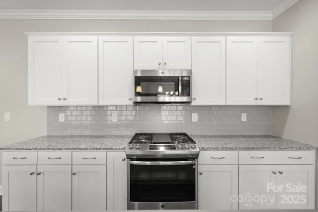 a kitchen with granite countertop white cabinets and a stove with a sink