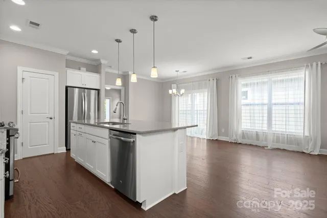 a kitchen with stainless steel appliances granite countertop a stove a sink a refrigerator and white cabinets with wooden floor