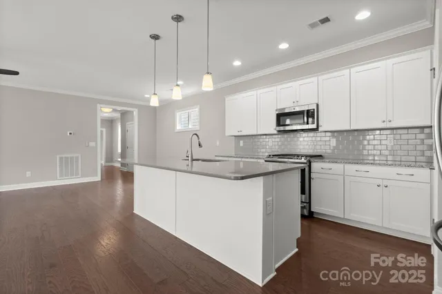 a kitchen with kitchen island granite countertop a sink cabinets and stainless steel appliances