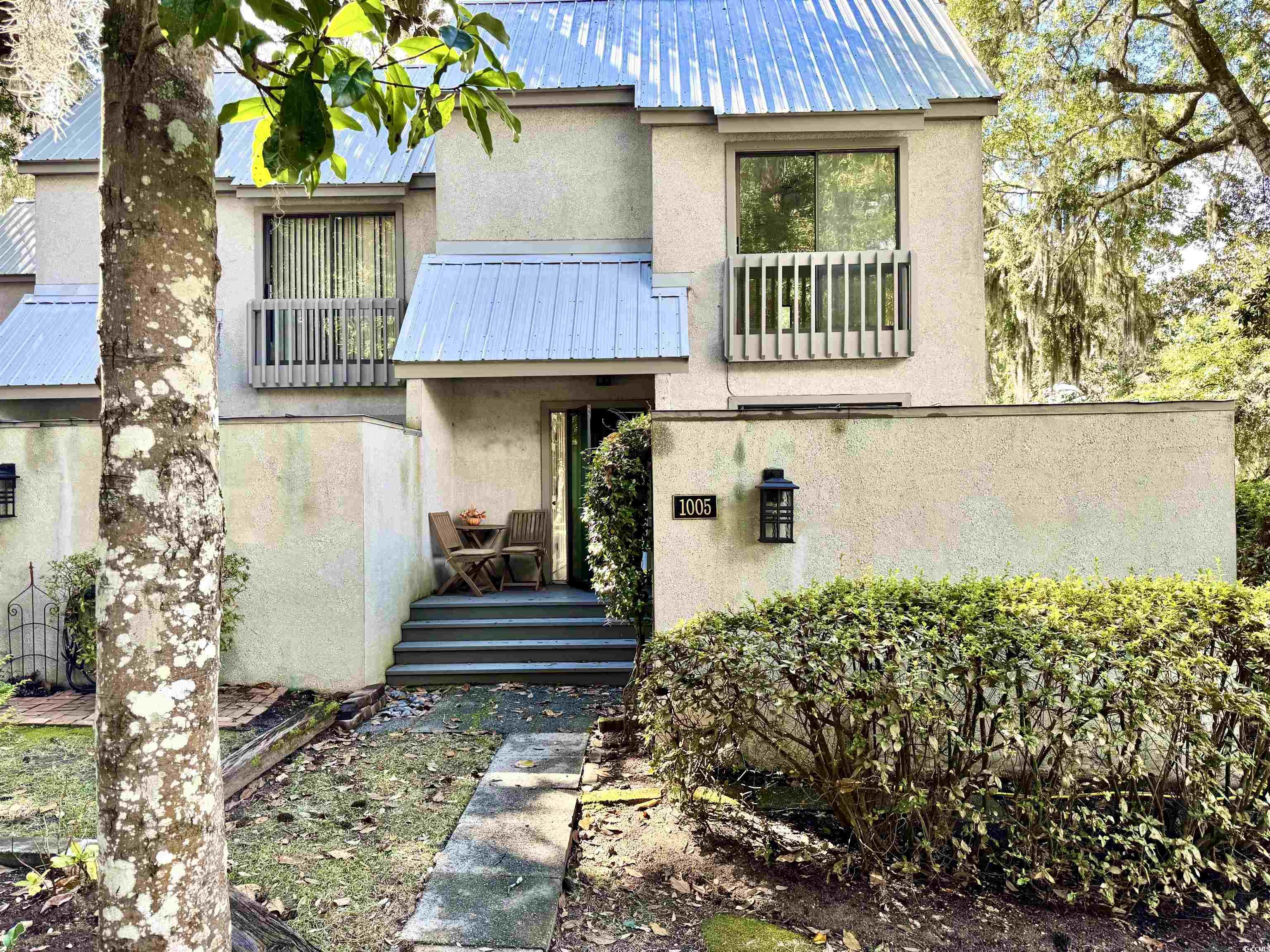 View of front of property with a balcony, a metal roof, and stucco siding