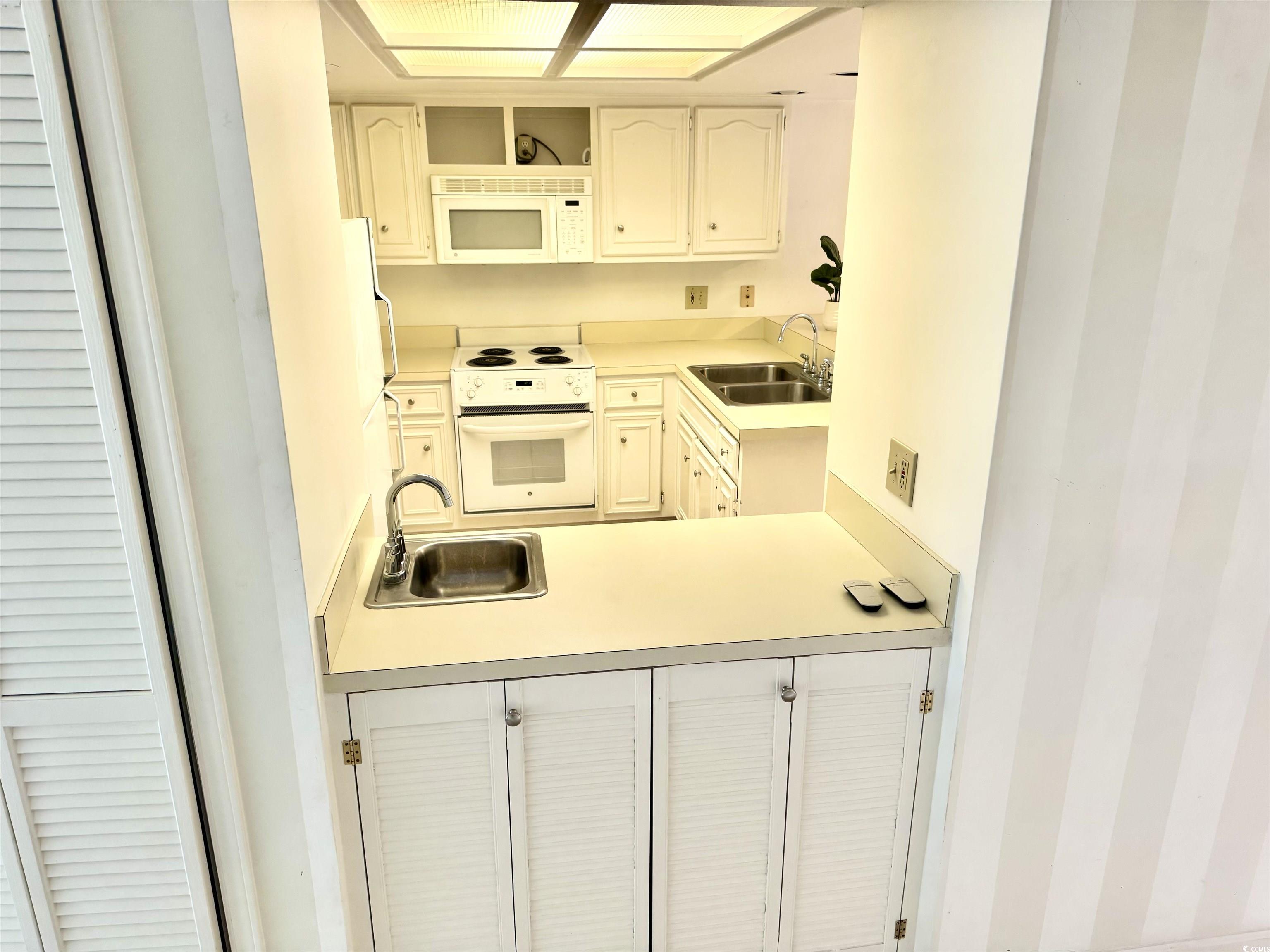 31 Battery White Court, Unit 1005 Georgetown, SC 29440 - Photo 12 of 34 Kitchen with light countertops, white appliances, open shelves, and white cabinetry