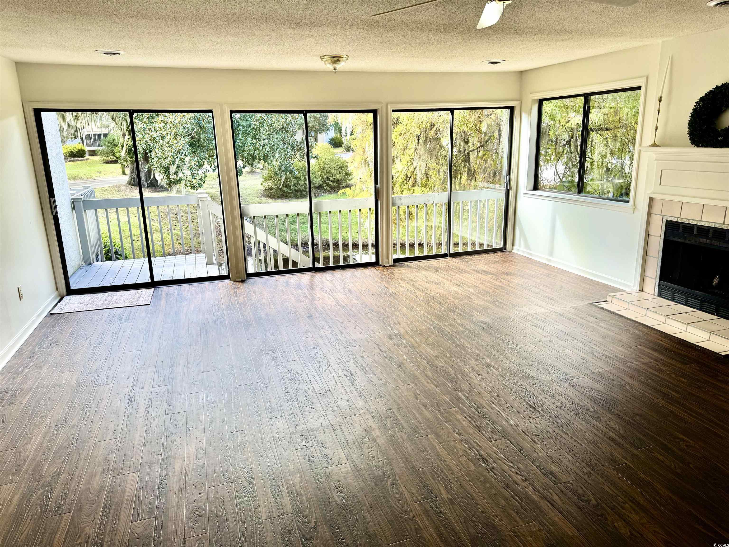 31 Battery White Court, Unit 1005 Georgetown, SC 29440 - Photo 2 of 34 Unfurnished living room featuring a textured ceiling, wood finished floors, a fireplace, and ceiling fan