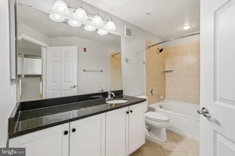 a bathroom with a granite countertop sink a toilet a mirror and shower