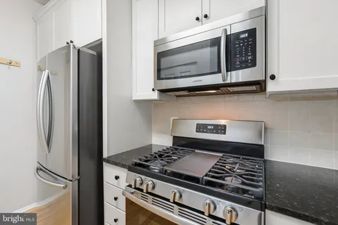 a kitchen with stainless steel appliances granite countertop a stove and a microwave with cabinets