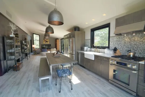 a kitchen with stainless steel appliances a dining table chairs stove and cabinets