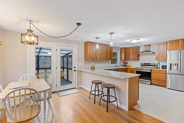 a kitchen with stainless steel appliances granite countertop a refrigerator a stove a sink dishwasher a dining table and chairs with wooden floor