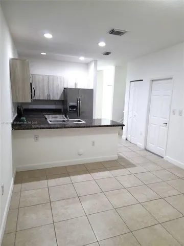 a view of kitchen with granite countertop cabinets and flat screen tv