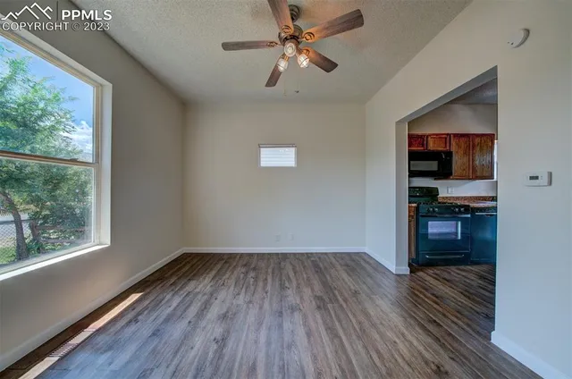 a view of empty room with wooden floor and fan