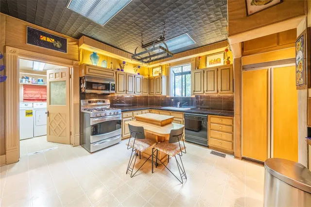 a kitchen with stainless steel appliances kitchen island granite countertop a stove and a refrigerator