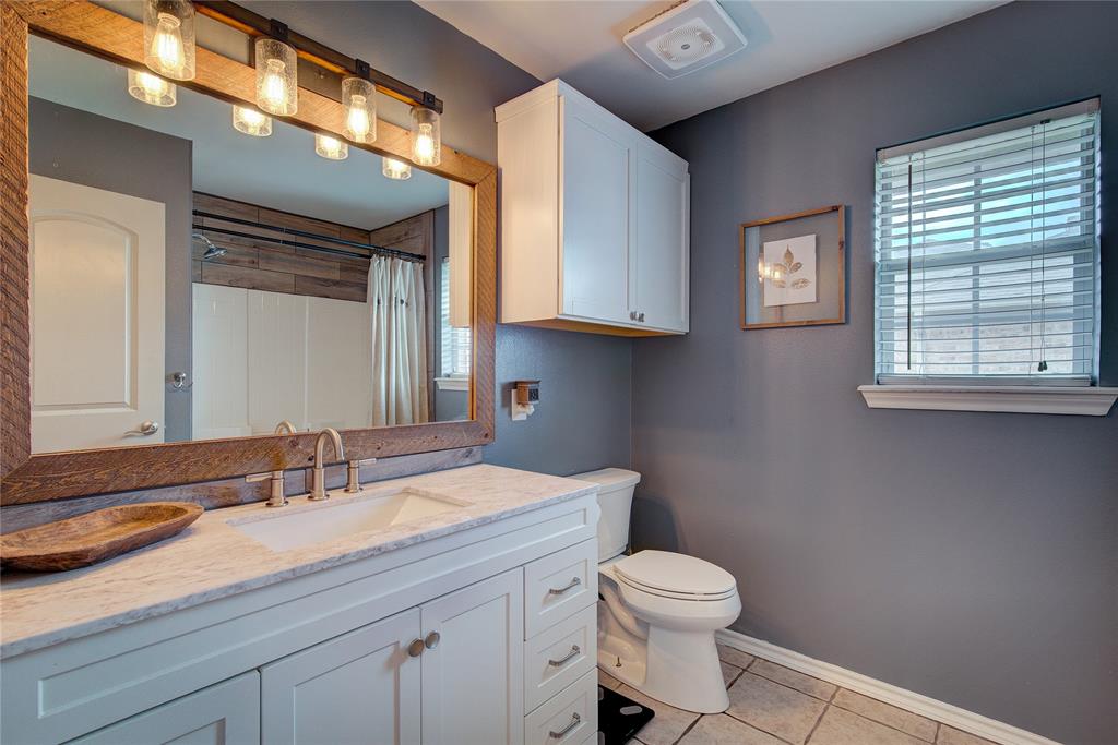 2027 Park Springs Road Sulphur Springs, TX 75482 - Photo 28 of 39 a bathroom with a granite countertop toilet a sink a mirror and a window