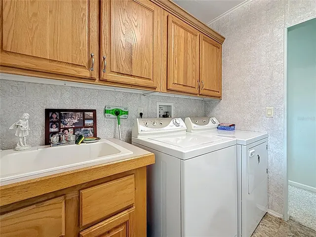 a utility room with stainless steel appliances a sink and cabinets