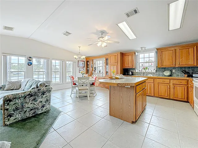 a kitchen with stainless steel appliances granite countertop a stove top oven a sink dishwasher and white cabinets with wooden floor