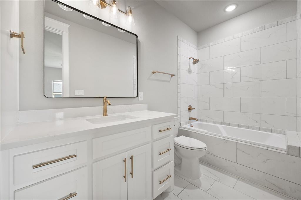 6610 Waggoner Way Midlothian, TX 76065 - Photo 33 of 40 Modern bathroom featuring a white vanity with gold-finish hardware, a rectangular undermount sink, and a large black-framed mirror