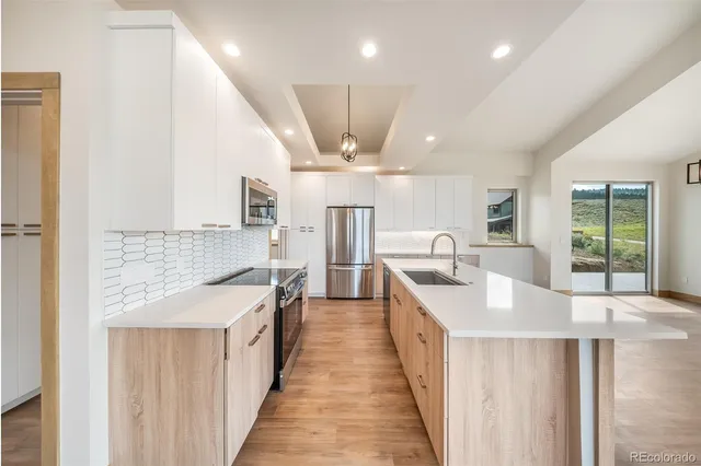 a large kitchen with granite countertop a large counter top space a sink stainless steel appliances and cabinets