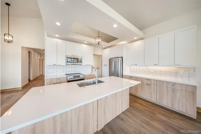 a large kitchen with stainless steel appliances kitchen island a large counter top a sink and a wooden floors